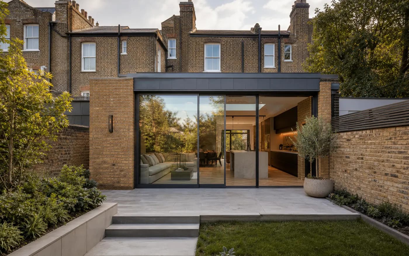 London rear kitchen extension with brickwork, dark glazing, and compact garden patio